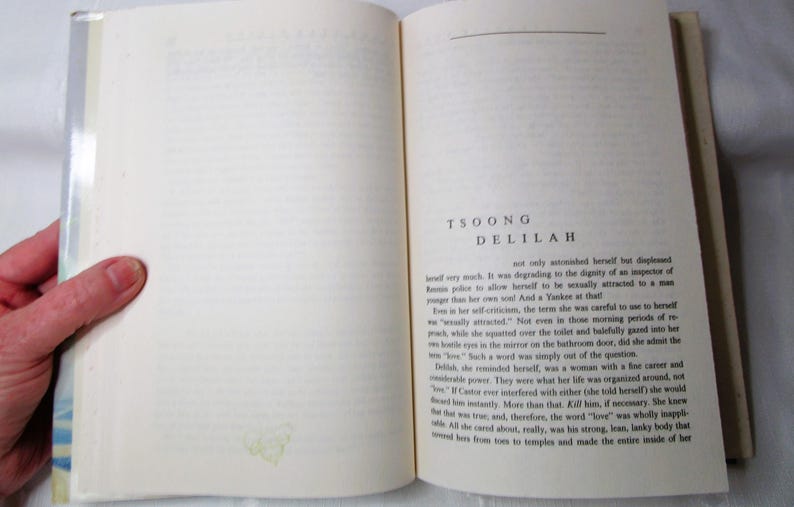 Puede incluir: Libro abierto con texto en la p&aacute;gina derecha y una mano sosteniendo la p&aacute;gina izquierda. El texto dice "TSOONG DELILAH". Las p&aacute;ginas del libro son de color blanquecino con texto negro.