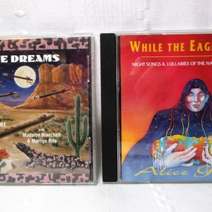 Puede incluir: Dos estuches de CD. El primero, "Flute Dreams", presenta un paisaje desértico con cactus, una luna llena y los nombres Alice Gomez, Madalyn Blanchett & Marilyn Rite. El segundo, "While the Eagle Sleeps", tiene un fondo rojo y una figura nativa americana.