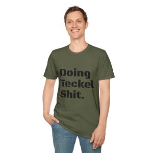 May include: A green t-shirt with the text "Doing teckel shit." printed in black.