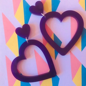 May include: A pair of purple heart-shaped earrings with a smaller heart charm on each earring.