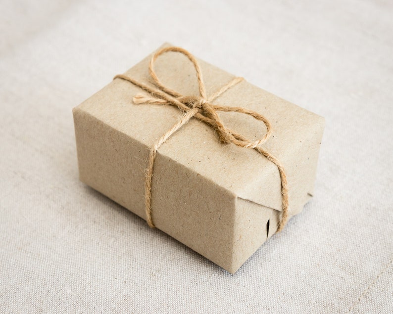 Op de afbeelding: Een bruine papieren cadeaudoos gebonden met touw. De doos is ingepakt in bruin papier en gebonden met touw, wat een eenvoudige en rustieke uitstraling cre&euml;ert.