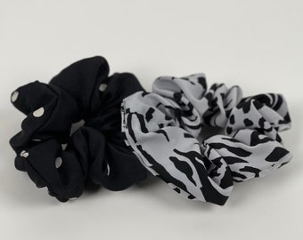 May include: Two hair scrunchies, one black with white polka dots and one grey with a black zebra print.