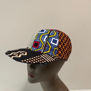May include: A black and brown baseball cap with a colorful patterned top. The pattern features geometric shapes in shades of blue, yellow, red, and orange.
