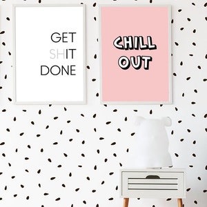 Może przedstawiać: Dwa oprawione wydruki z motywującymi frazami wiszą na białej ścianie z czarnymi plamkami. Jeden m&oacute;wi "GET SHIT DONE", drugi "CHILL OUT". Poniżej znajduje się biała szafka nocna z drewnianymi nogami.