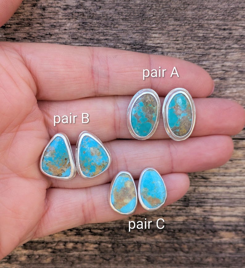 May include: Three pairs of turquoise stud earrings with silver settings. Pair A has oval stones, pair B has triangular stones, and pair C has teardrop-shaped stones. The turquoise stones have a mix of blue and brown hues.