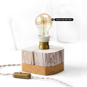 Puede incluir: Una base de lámpara de madera blanca con fondo de corcho y una bombilla de estilo Edison A60 40W dorada.