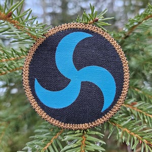 May include: A blue and brown embroidered patch with a stylized three-pointed star design.