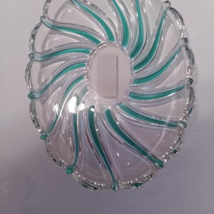 May include: Oval-shaped clear glass serving dish with teal swirl design. The dish has a scalloped edge and a central oval area. The teal accents create a spiral pattern, adding a decorative touch to the glassware.