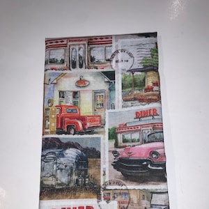 May include: A vintage-style fabric with a collage of images depicting diners, cars, and roadside scenes. The fabric features a red, white, and blue color scheme with a distressed look. The text "DINER" appears multiple times on the fabric.