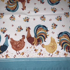 May include: A white fabric with a repeating pattern of roosters and floral designs. The roosters are in shades of brown, blue, and yellow. The floral designs are in shades of yellow and brown.