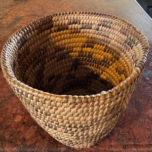 May include: A white ceramic mug with a black handle and the text "But First, Coffee" in a black, bold font. The mug is on a white surface.