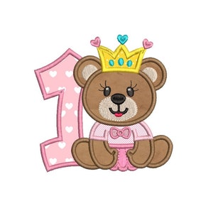 以下が含まれることがあります： ピンクと白の数字1と、黄色の王冠とピンクのドレスを着た茶色のテディベア。テディベアは胸にピンクのリボンをつけています。