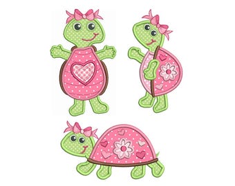 May include: Three embroidered applique designs of a turtle wearing a pink dress with a heart and flowers. The turtle has green legs and a green head with a pink bow.
