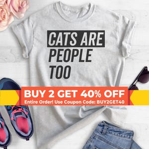 May include: A light gray short-sleeved t-shirt featuring the black text CATS ARE PEOPLE TOO centered on the chest. An orange promotional banner across the middle displays the text BUY 2 GET 40% OFF Entire Order! Use Coupon Code: BUY2GET40.