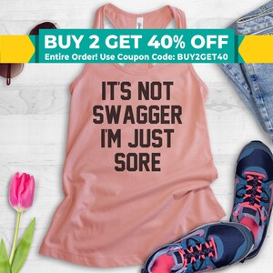 May include: A pink tank top with the text "It's not swagger I'm just sore" in black lettering.