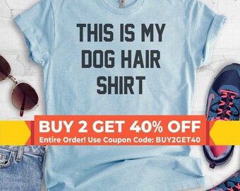 Puede incluir: Una camiseta de manga corta de color azul claro con el texto negro THIS IS MY DOG HAIR SHIRT impreso en la parte delantera. La camiseta se muestra junto a unas gafas de sol, unos vaqueros azules y unas zapatillas deportivas azules y rosas.