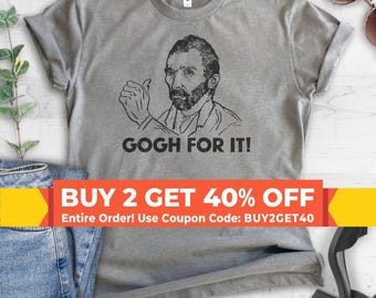 May include: A heather gray short-sleeve t-shirt featuring a black line-art illustration of Vincent van Gogh giving a thumbs-up gesture. Below the illustration, the text reads GOGH FOR IT! in a bold, black, sans-serif capital letter font.