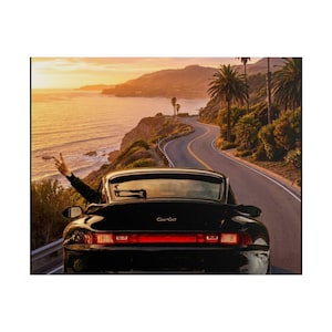 May include: A black sports car with the word "Turbo" on the back, driving along a scenic coastal road at sunset. Palm trees and ocean views are visible in the background. A person is giving the peace sign out the window.