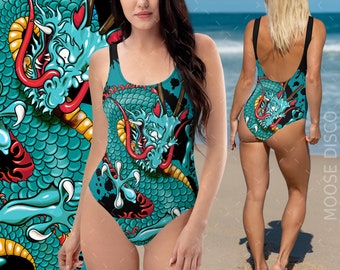 May include: A turquoise and black one-piece swimsuit with a graphic print of a blue dragon. The dragon has red accents and is set against a black background.