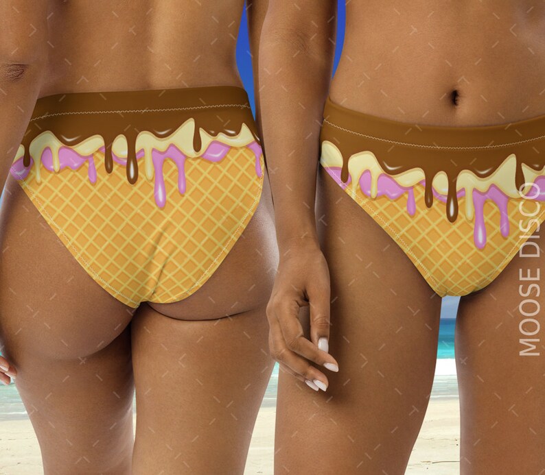 May include: A brown and white bikini bottom with a waffle cone design and pink and brown dripping ice cream. The bikini bottom is on a model.