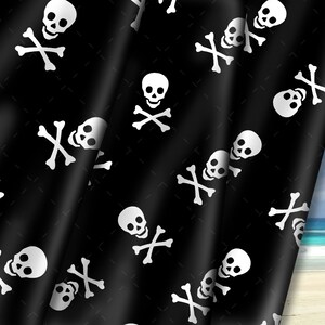 May include: Black fabric with a white skull and crossbones pattern. The fabric is folded over and the background is a blue sky and beach.
