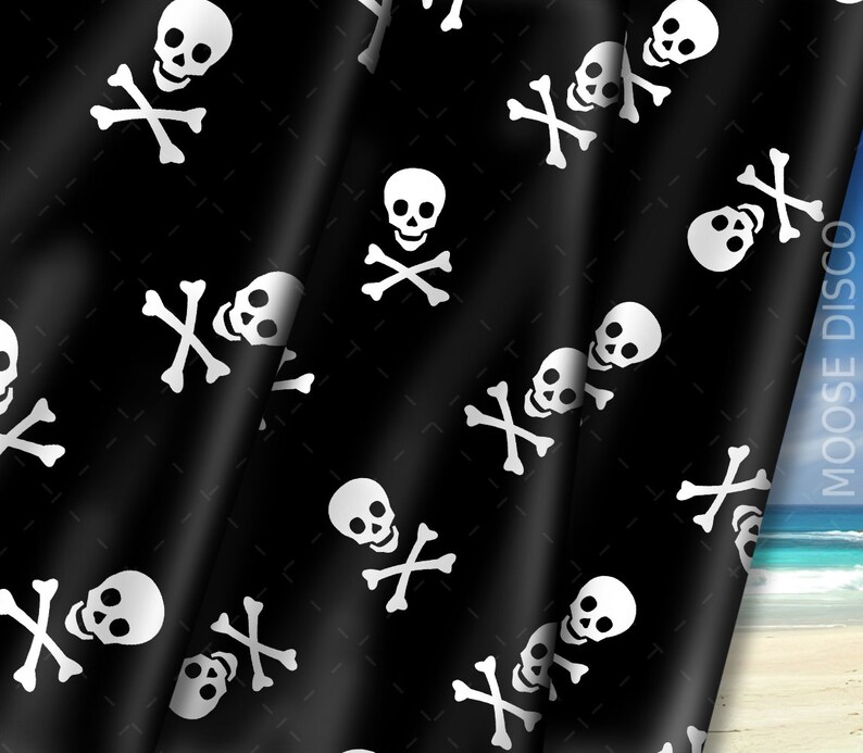 May include: Black fabric with a white skull and crossbones pattern. The fabric is folded over and the background is a blue sky and beach.