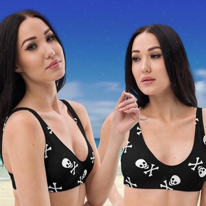 May include: Two black bikini tops with a white skull and crossbones pattern. The tops have a scoop neck and adjustable straps.