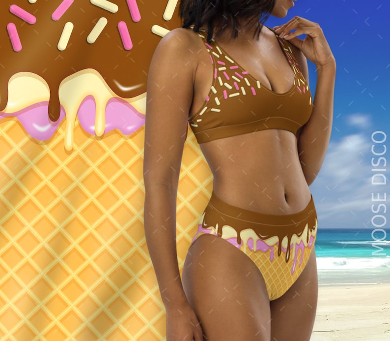 May include: A brown and pink bikini with a waffle cone and ice cream design. The top and bottom of the bikini have a brown chocolate-like design with pink and white sprinkles. The bottom of the bikini has a pink and white ice cream design with a waffle cone pattern.