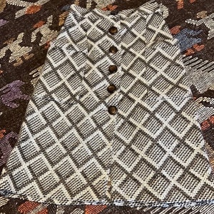 May include: A brown and white geometric patterned skirt with a button closure. The skirt is made of a woven fabric.