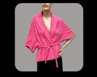 May include: A pink wrap jacket with a wide collar and a tie belt. The jacket has a pocket on each side and is made of a soft, lightweight fabric.
