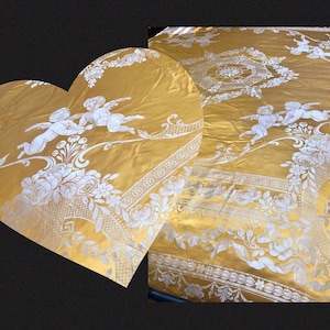 May include: A gold and white damask fabric with a repeating pattern of cherubs and floral motifs. The fabric has a luxurious and elegant feel.