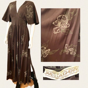 May include: A long brown maxi dress with a floral print and a V-neckline. The dress has short sleeves and a fitted bodice. The dress is made of a soft, flowing fabric and has a side slit. The dress has a label that reads "JAMES DAUGHERTY DRY CLEAN ONLY".