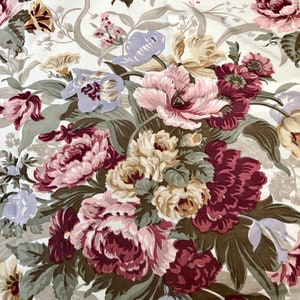 May include: A white fabric with a floral pattern featuring pink, purple, and burgundy flowers with green leaves.