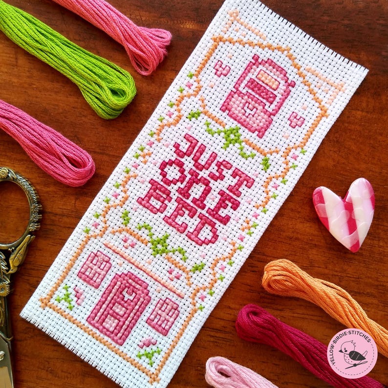 May include: Cross stitch pattern with a pink and green design. The pattern says "Just one bed".