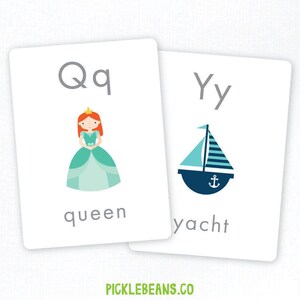 Op de afbeelding: Twee witte flashcards met de letters 'Qq' en 'Yy'. De 'Qq'-kaart toont een cartoonkoningin in een turquoise jurk en het woord 'queen'. De 'Yy'-kaart toont een blauw-witte jacht, met het woord 'yacht'. Het websiteadres 'picklebeans.co' staat onderaan.
