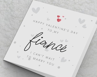 Puede incluir: Tarjeta blanca con el texto "Happy Valentine's Day to my fiance I can't wait to marry you" en texto negro. La tarjeta está decorada con pequeños corazones rojos y grises.