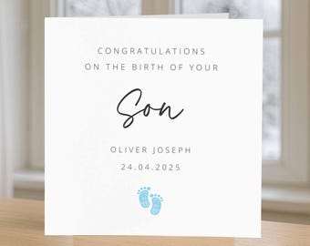 May include: A white card with the text "CONGRATULATIONS ON THE BIRTH OF YOUR Son" in black. Below is the name "OLIVER JOSEPH" and the date "24.04.2025". Two blue baby footprints are at the bottom.