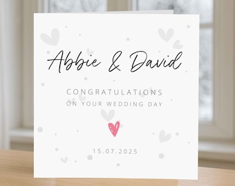 May include: A white wedding card with the names "Abbie & David" in elegant script. The card includes the text "Congratulations on your wedding day" and the date "15.07.2025", with scattered heart illustrations.