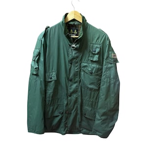 Peut inclure: Une veste Barbour vert foncé dotée d'un col montant, d'une fermeture éclair frontale avec une tirette en anneau métallique et de multiples poches à boutons-pression sur la poitrine et les manches. L'intérieur est doublé d'un tissu à carreaux.