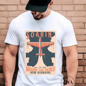 May include: A white t-shirt with a vintage-style graphic of a red airplane soaring through the clouds. The graphic says "Soarin' Around the World Now Boarding".