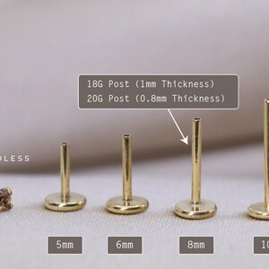 May include: Five gold-colored, threadless end, labret studs in different lengths: 5mm, 6mm, 8mm, and 10mm. The text "18G Post (1mm Thickness)" and "20G Post (0.8mm Thickness)" is visible above the studs.