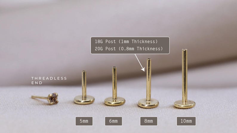 May include: Five gold-colored, threadless end, labret studs in different lengths: 5mm, 6mm, 8mm, and 10mm. The text "18G Post (1mm Thickness)" and "20G Post (0.8mm Thickness)" is visible above the studs.