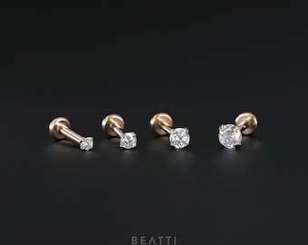 May include: Three rose gold stud earrings with a single clear round gemstone in each. The earrings are arranged in a row from smallest to largest.
