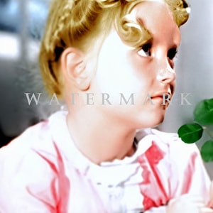 May include: A young girl with blonde hair styled in curls and braids, wearing a pink and white dress, looks to the side.