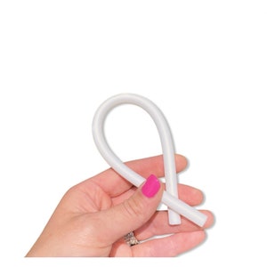 Puede incluir: Un tubo de silicona blanco flexible, doblado en forma de bucle.