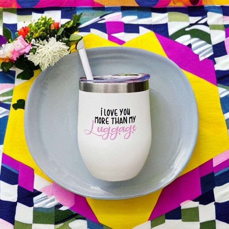 Puede incluir: Un vaso t&eacute;rmico de acero inoxidable blanco con una inscripci&oacute;n rosa y negra que dice "i love you more than my luggage". El vaso tiene una tapa y una pajita.