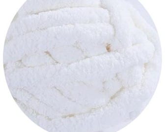 May include: Close-up of a ball of white, chunky yarn. The yarn is thick and fluffy, with a soft, textured appearance. The word "White" is printed at the bottom of the image.