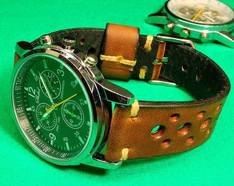 Könnte beinhalten: Eine silberne Chronographen-Armbanduhr mit grünem Zifferblatt und einem braunen Lederarmband mit Löchern. Das Armband hat weiße Nähte.