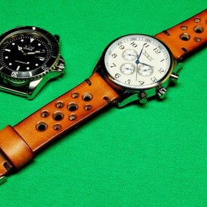 May include: A brown leather watch strap with holes and a silver chronograph watch with a white face. The watch has a blue second hand and the text "Timex" on the face.