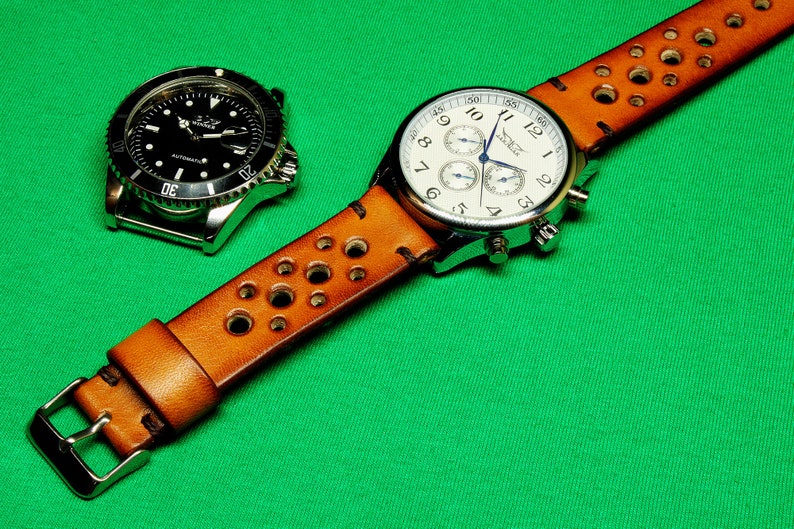 May include: A brown leather watch strap with holes and a silver chronograph watch with a white face. The watch has a blue second hand and the text "Timex" on the face.